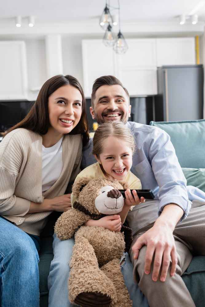 Cheerful,Girl,Holding,Remote,Controller,While,Watching,Tv,With,Happy