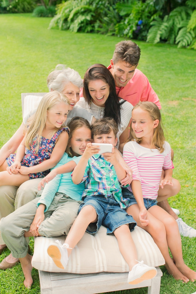 Family,Using,Cell,Phone,Together,In,Backyard